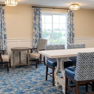 A well-decorated dining room with patterned chairs and curtains, featuring a large table and elegant lighting.