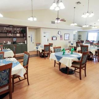 A spacious dining area with neatly arranged tables and chairs, featuring warm lighting fixtures.