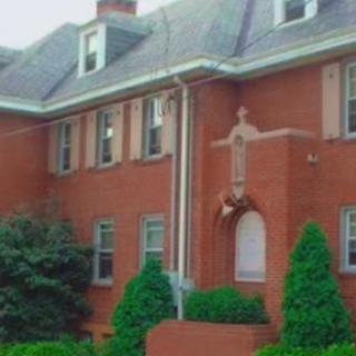A view of a brick residence featuring classic architectural elements and well-maintained landscaping.