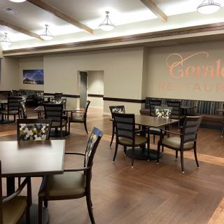 A spacious dining area with neatly arranged tables and chairs under modern lighting.