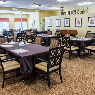 A well-arranged dining room with multiple tables and chairs, featuring decorative wall art.