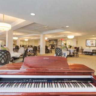 A grand piano in an elegant dining area with chandeliers.