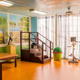 A well-lit rehabilitation room equipped with exercise equipment and therapeutic stairs.