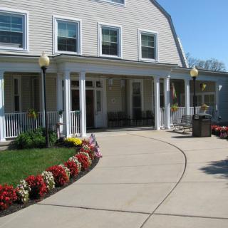 A house with a landscaped pathway lined with flowers leading to a porch.
