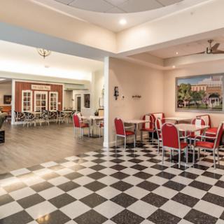 A spacious dining area featuring a classic checkered floor and red seating.