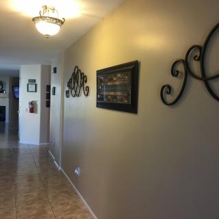 A well-lit hallway featuring decorative wall art and tiled flooring.