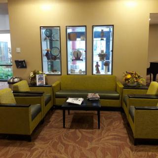 A cozy and inviting waiting area featuring green sofas, a coffee table, and decorative plants.