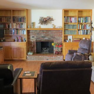 A cozy living room with wooden bookshelves flanking a brick fireplace, adorned with comfortable armchairs.