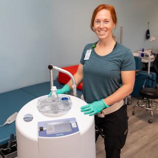 A healthcare professional stands beside medical equipment, ready to assist patients.