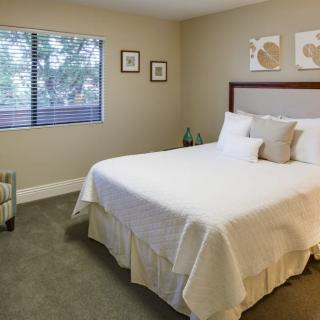 A minimalist bedroom with a neatly made bed and framed artwork on the walls.