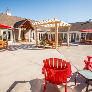 A sunny courtyard with a pergola and colorful outdoor seating.