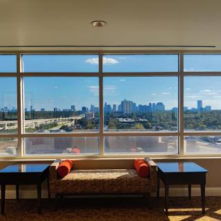 A spacious room with large windows overlooking a city skyline.