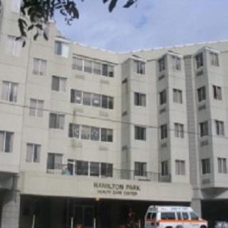 A modern hospital building featuring multiple floors and a clear sky in the backdrop.