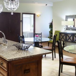 A modern kitchen and dining area with a granite island and elegant chandeliers.