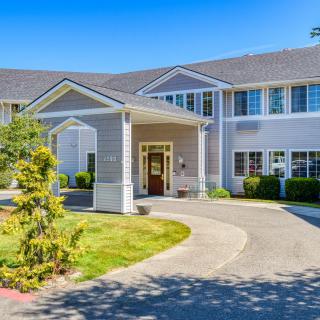 A residential-style building with a driveway and landscaped surroundings.