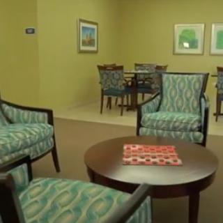 A comfortable waiting room with patterned chairs, small tables, and framed artwork on the walls.