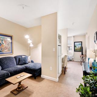 A cozy living room featuring a dark blue sofa, artwork on the wall, and a stylish floor lamp.