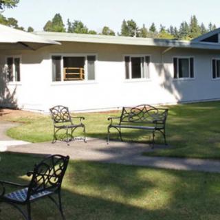 A sunny outdoor area with benches and a pathway in front of a building.