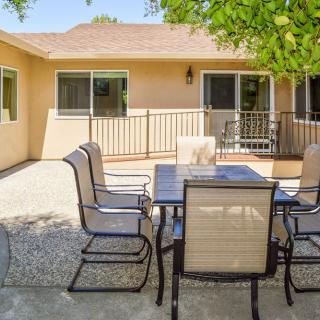 A sunny backyard patio area with a table and chairs.