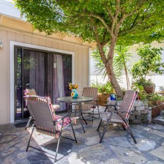 A cozy patio setup with chairs and a table under the shade of a tree.