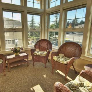 A bright and cozy sunroom featuring wicker furniture and large windows.