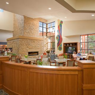 A welcoming lobby featuring a stone fireplace and comfortable seating, illuminated by natural light from large windows.