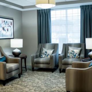A cozy living room with several armchairs arranged around a central table, complemented by elegant lamps and curtains.