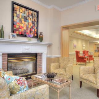A cozy living room with a fireplace, comfortable seating, and colorful artwork on the wall.
