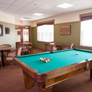 A well-lit game room featuring a pool table and seating area.