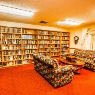 A cozy library interior with bookshelves, couches, and a table.