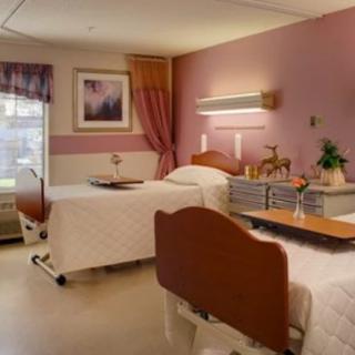 A well-lit hospital room with two beds, decorated in warm tones.