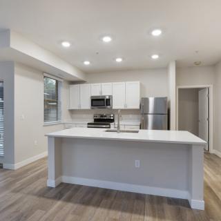 A modern kitchen with an open concept design featuring a central island, stainless steel appliances, and recessed lighting.