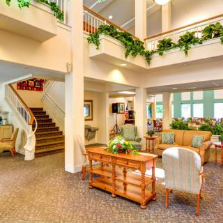 A bright and cozy lobby with comfortable seating, decorative plants, and staircase access.