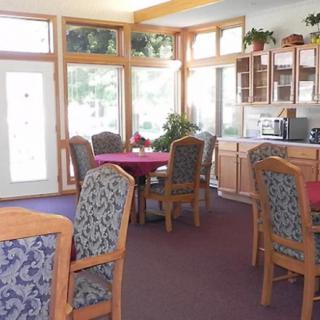 A bright and inviting dining area with several tables and chairs, surrounded by large windows that let in natural light.