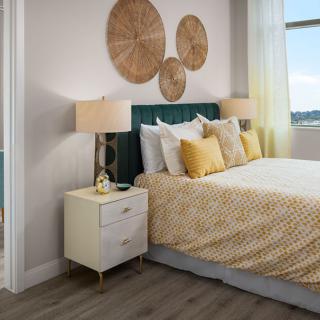 A stylish bedroom with modern decor, featuring a comfortable bed, bedside tables with lamps, and textured wall art.