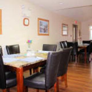 A cozy dining area with wooden tables and black leather chairs.