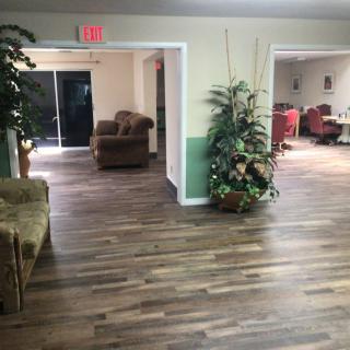 A spacious lobby area with wood flooring, featuring comfortable seating and decorative plants.
