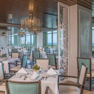 A beautifully set dining area in an elegant restaurant with chandeliers and neatly arranged tables.