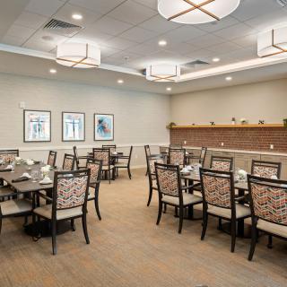 A well-lit dining room with several arranged tables and chairs, featuring elegant interior design.