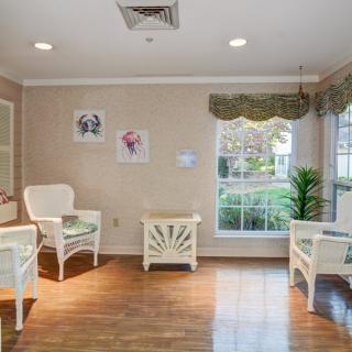 A cozy waiting room with chairs, a small table, and large windows allowing natural light.