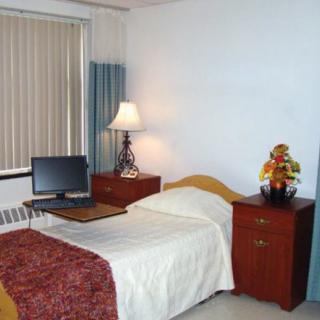 A simple hospital room with a single bed, desk, and computer monitor.