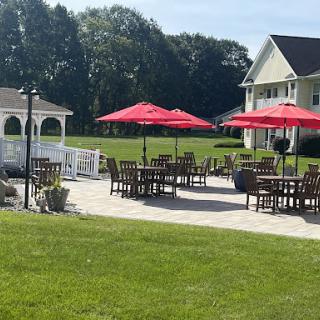 A sunny outdoor patio area featuring red umbrellas and wooden furniture, perfect for relaxation.
