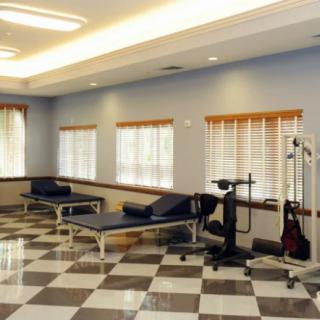 A bright and spacious physical therapy room with treatment tables and exercise equipment.
