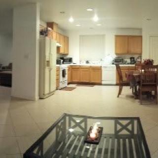 A modern kitchen and dining area with wooden cabinets and a glass coffee table.
