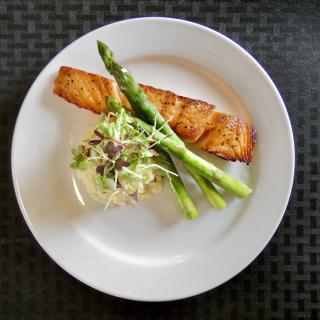 A plate of gourmet salmon served with asparagus and garnished vegetables.