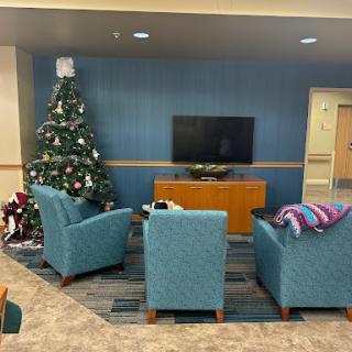 A cozy living room space decorated with a Christmas tree and comfortable seating, perfect for relaxation.