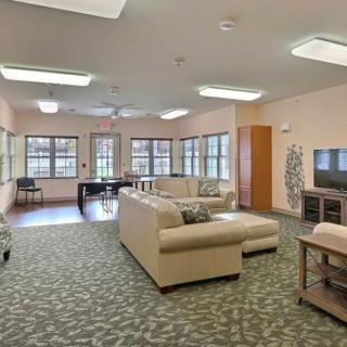 A spacious living room featuring comfortable sofas, a television, and large windows allowing natural light.
