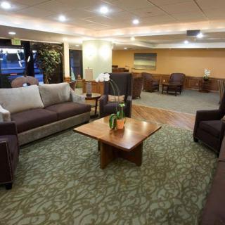 A cozy lobby area with sofas, armchairs, and a central wooden table.