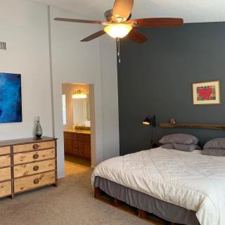 A modern bedroom featuring a large bed, a wooden dresser, and colorful artwork on the walls.