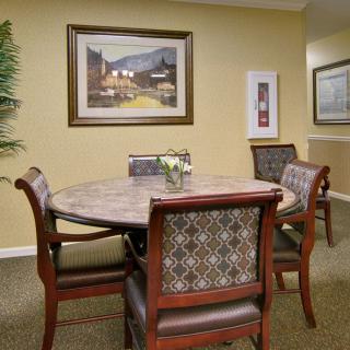 A cozy dining area with a round table, cushioned chairs, and decorative artwork on the walls.